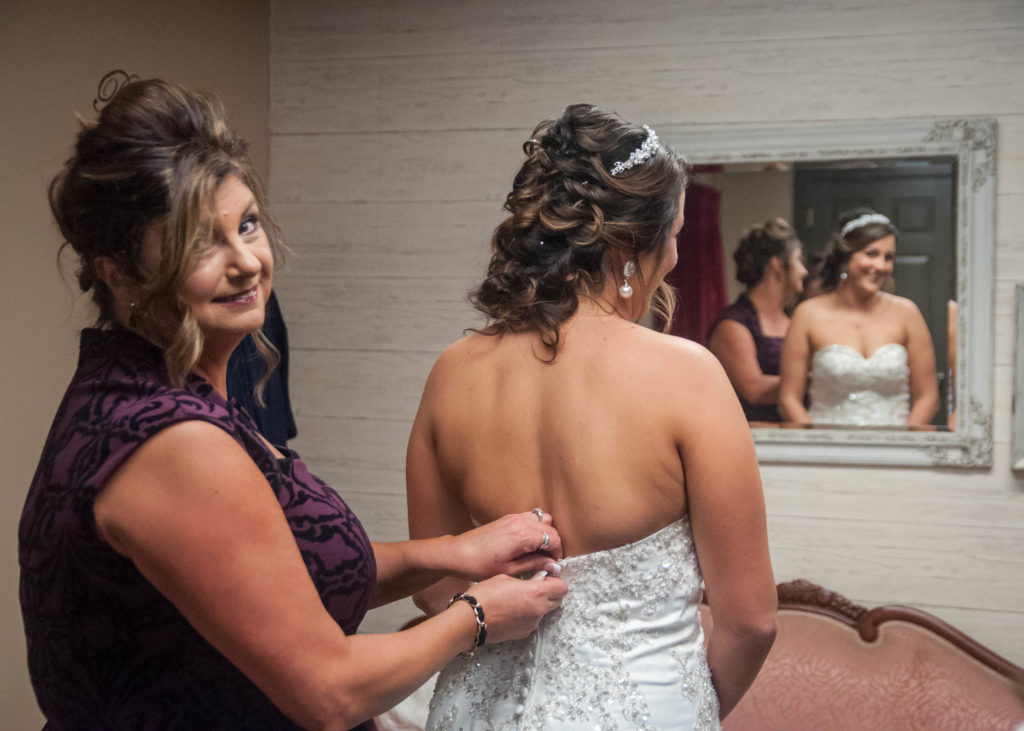 mother helping daughter into wedding gown